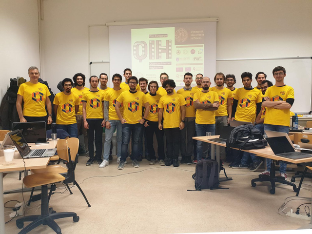 A group of hackathon participants stand together in yellow Hackathon t-shirts